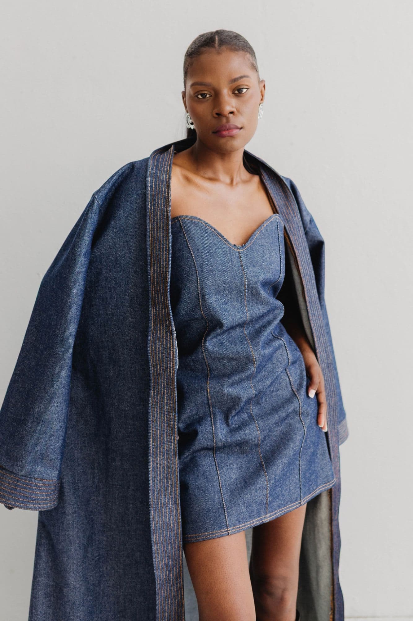 the muse, denim overcoat worn over a corseted denim mini dress